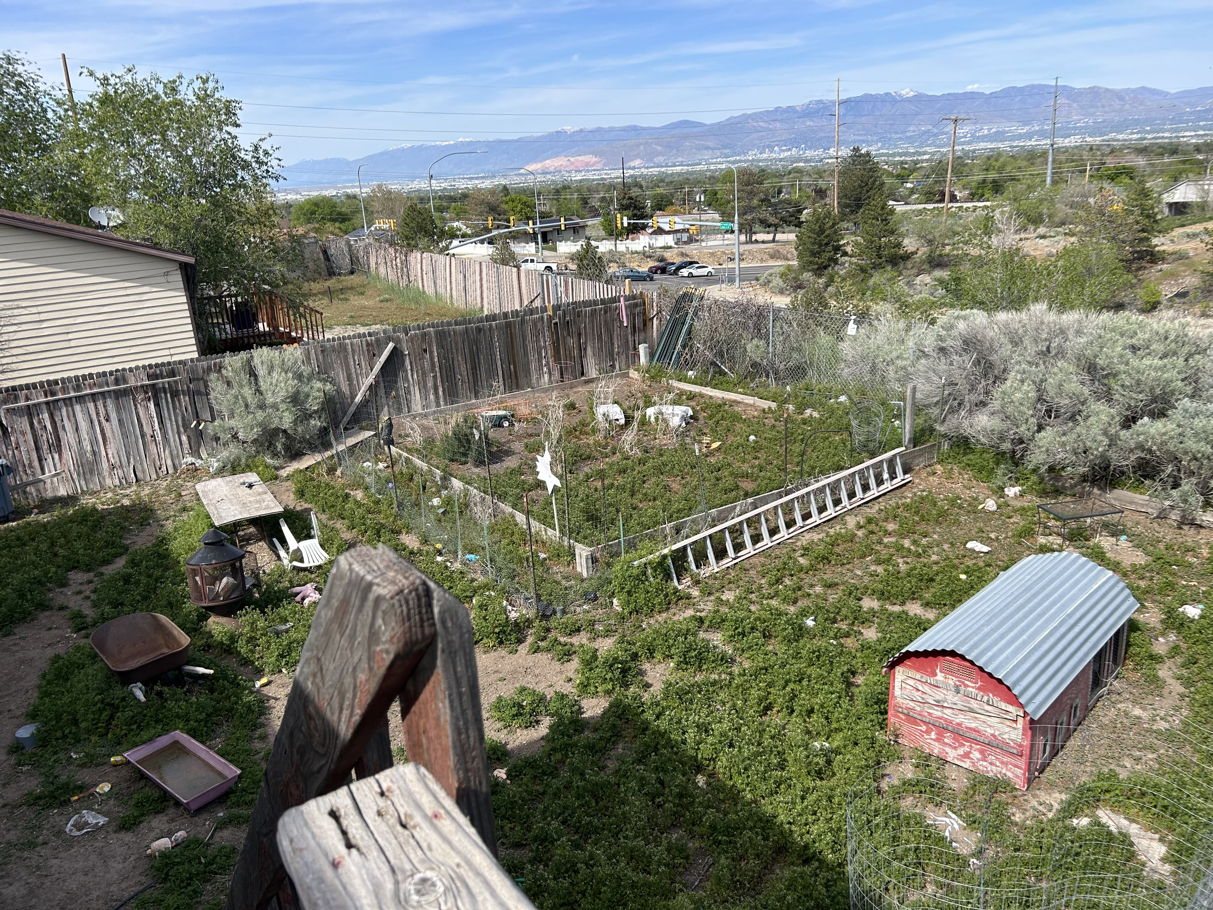 Expansive outdoor area featuring a fenced garden plot, slatted wood fencing, and distant mountain scenery