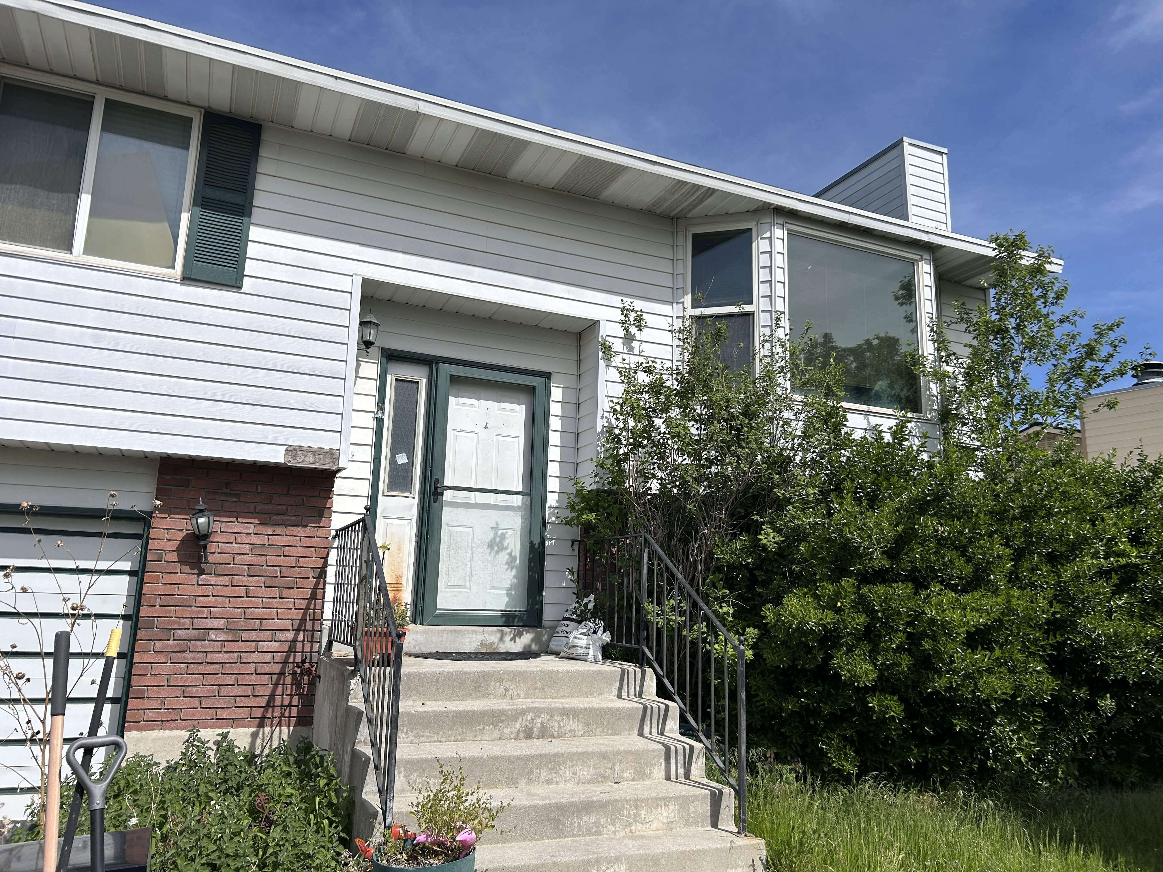 Split-level residence featuring white siding and brick accents