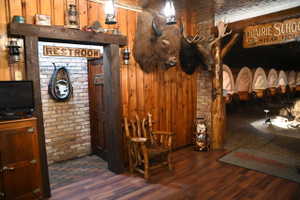 Wood-finish flooring throughout, complemented by wood-paneled walls and exposed brick accents