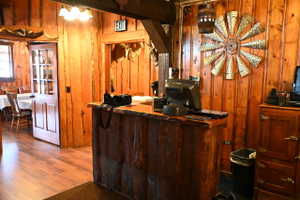 Rustic wood-paneled interior featuring a live-edge wood counter, wood-finish flooring, and an adjacent room with a wood-paneled door