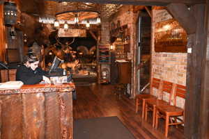 Rustic entry featuring wood-finish flooring, exposed brick walls, a wood-paneled reception counter, and a wagon wheel light fixture