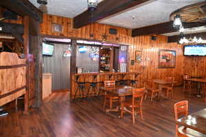 Spacious interior featuring extensive wood paneling, wood-finish flooring, and exposed ceiling beams