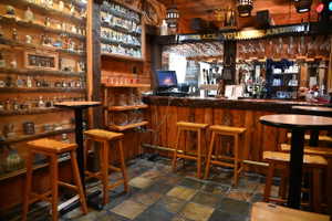 Rustic-themed entertainment space featuring a custom wood-plank bar with integrated shelving and overhead glass racks