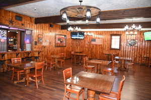 Spacious interior featuring wood-finish flooring, vertical wood paneling, and exposed wood ceiling beams