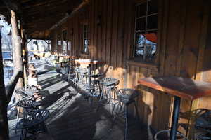 Expansive covered porch featuring a wood plank floor and a natural wood log support structure