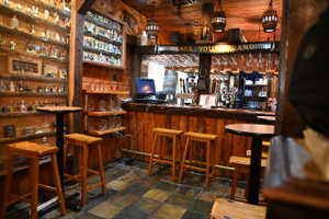 Custom wood-paneled bar area featuring a built-in bar, wood-finish flooring, and integrated shelving