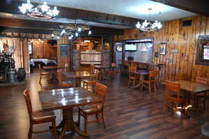 Spacious interior featuring wood-finish flooring, plank wood wall coverings, and decorative wagon wheel light fixtures