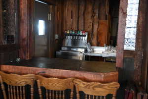 Rustic-style bar area featuring a substantial wood-finish countertop, wood plank wall paneling, and decorative glass block accents