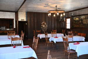 Dining area featuring wood-finish wall paneling, tin-look ceiling tiles, and wood-finish flooring