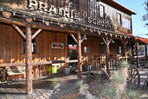 Rustic wood-sided building featuring a porch with log pillars and wood plank flooring