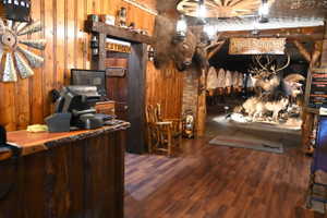 Reception area featuring wood-finish flooring, knotty pine paneling, a live-edge countertop, and a rustic wagon wheel ceiling fixture