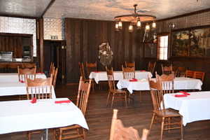 Spacious room featuring wood-finish flooring, dark wood paneling, and textured ceiling panels