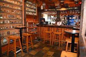 Custom bar area featuring wood-finish paneling, a built-in shelving system, and slate tile flooring