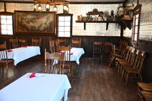 Spacious dining area featuring wood-finish flooring, dark wood paneling, and a unique pressed tin ceiling