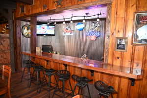 Custom bar area featuring rich wood-finish paneling, a glossy countertop, and corrugated metal wall accents