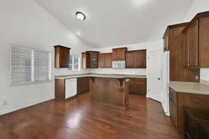 Kitchen featuring vaulted ceilings, wood-finish flooring, wood cabinetry, light countertops, and a built-in microwave