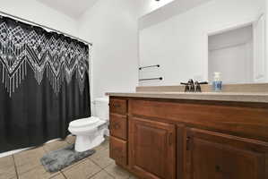 Bathroom featuring a wood-finish vanity with a light-toned countertop, a rectangular mirror, and a white toilet