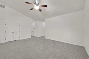 Spacious living room featuring vaulted ceilings, light gray carpeting, and a ceiling fan with integrated lighting