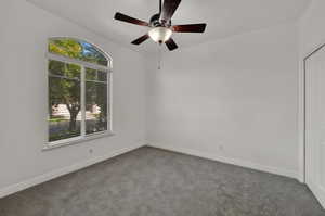 2nd Bedroom with arch-top window with blinds, ceiling fan with light fixture, gray carpeting, and white walls