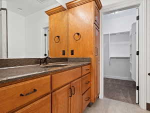 Master bathroom featuring a dark countertop, undermount sink with bronze-finish faucet and walk-in-closet