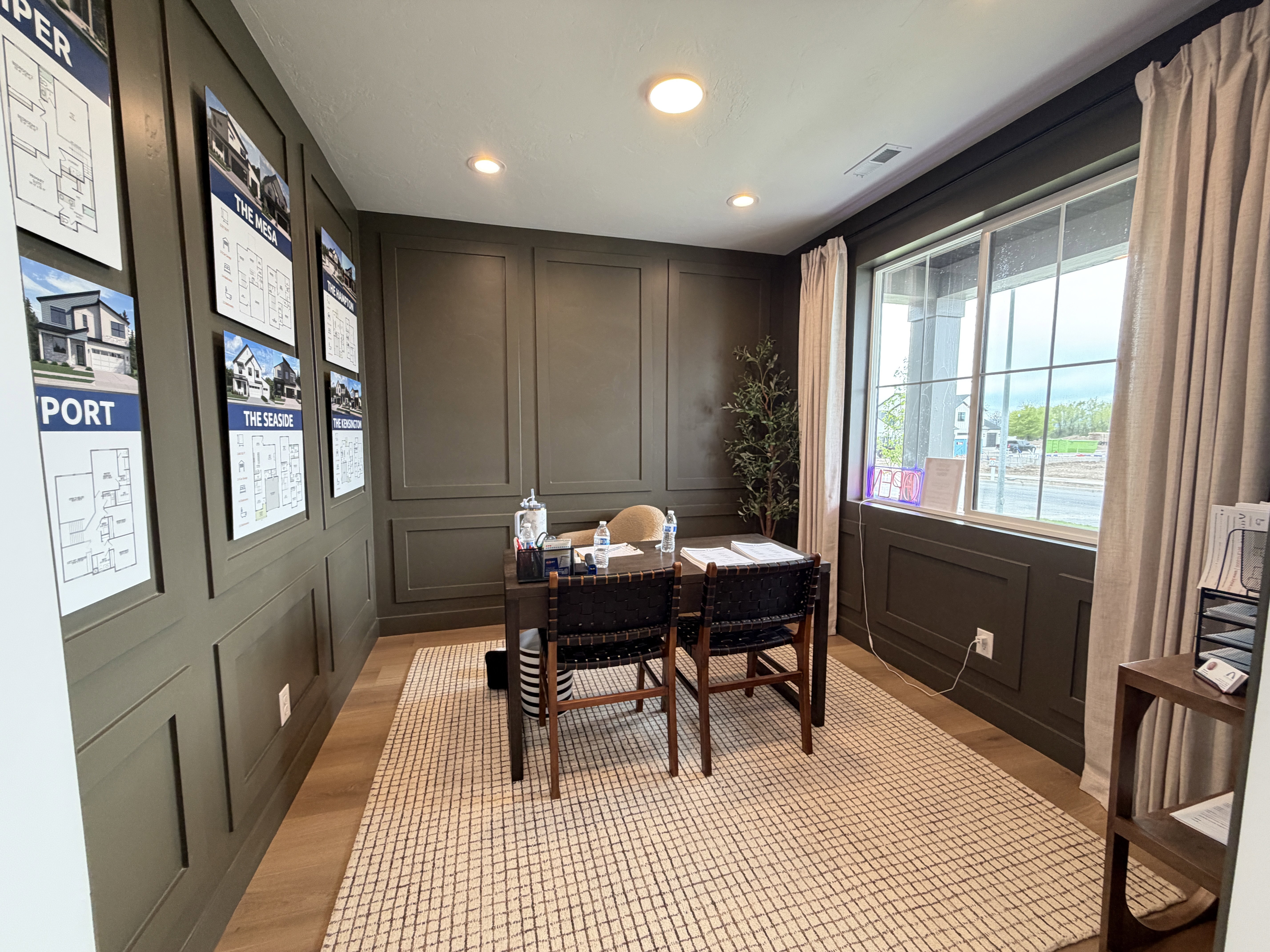 Dedicated office space featuring full wall paneling, recessed lighting, a large picture window with drapes, and wood-finish flooring