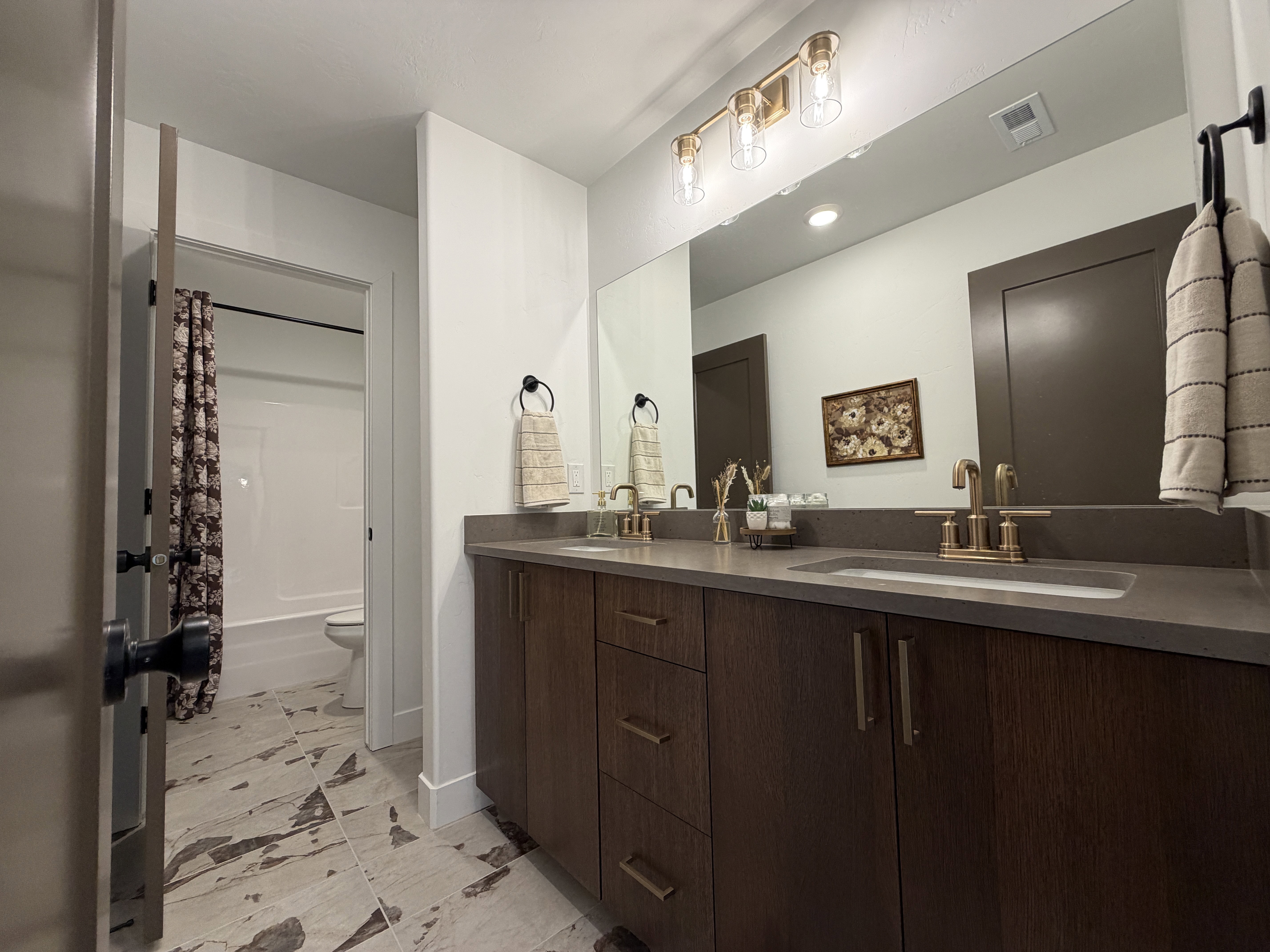 Double vanity with wood-finish cabinetry, integrated rectangular sinks, and a dark countertop