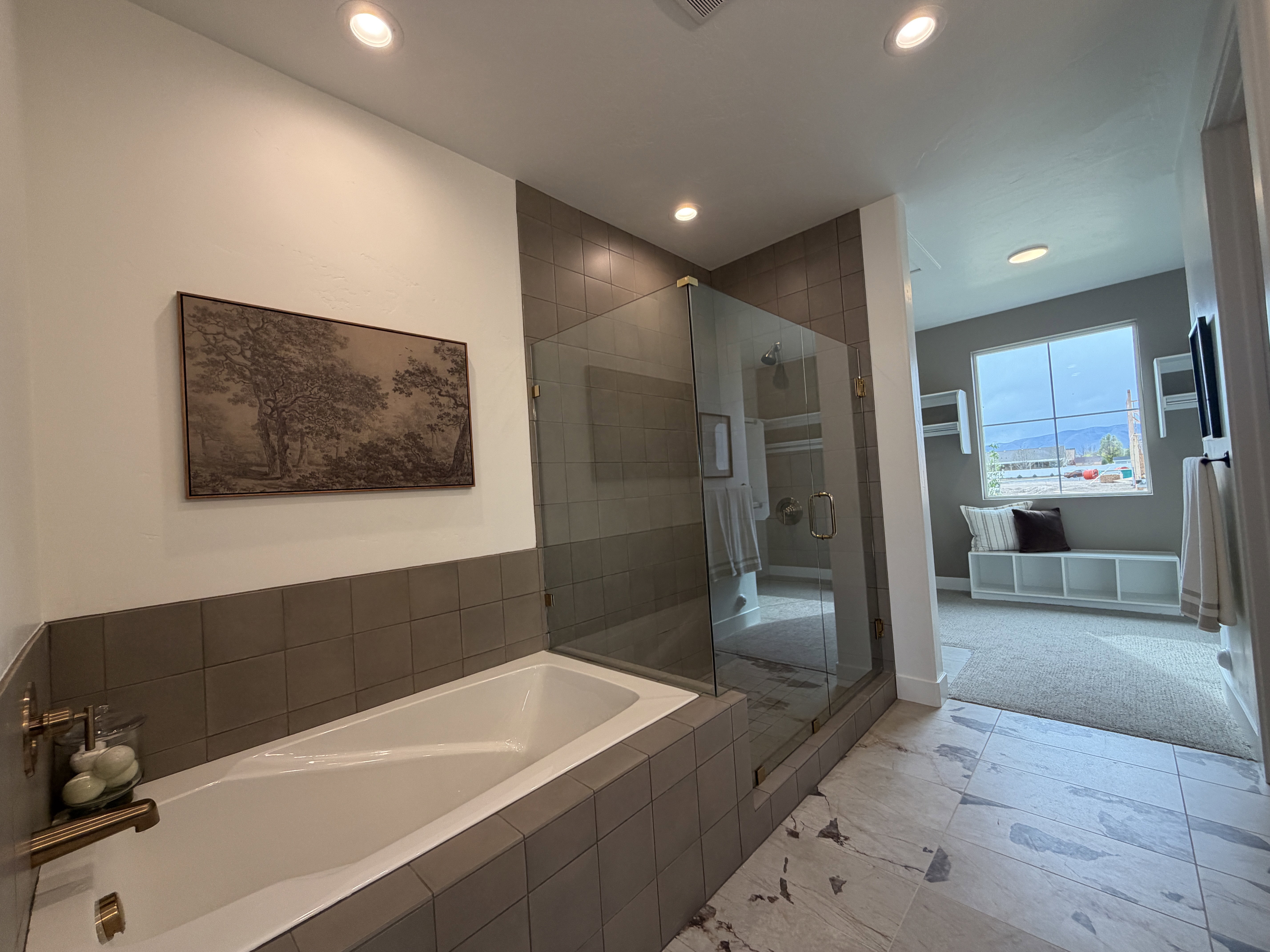 Soaking tub with a tiled surround, glass-enclosed shower, and large format marble-look flooring