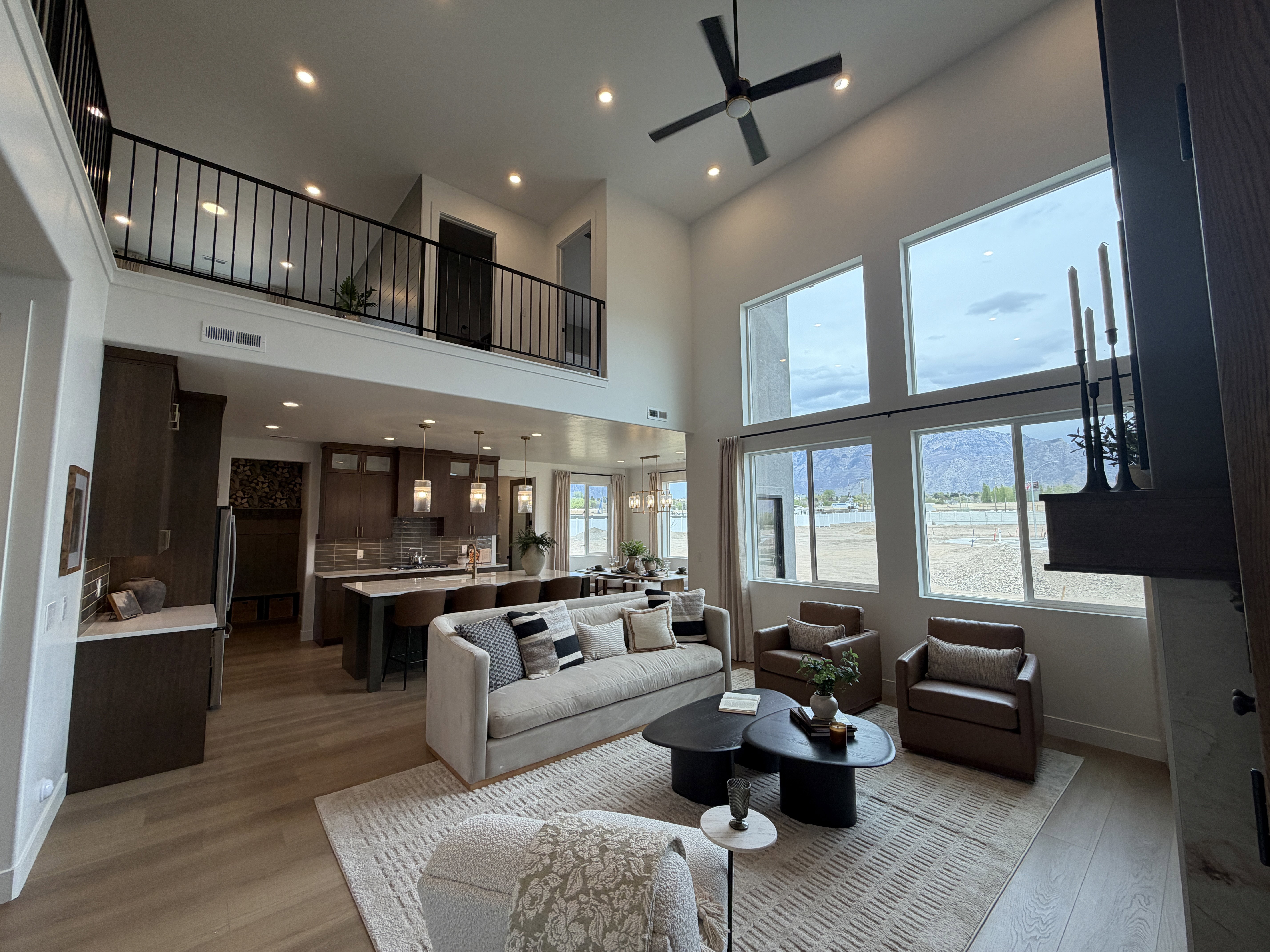 Spacious living area featuring a two-story ceiling, a large ceiling fan, and extensive window arrays
