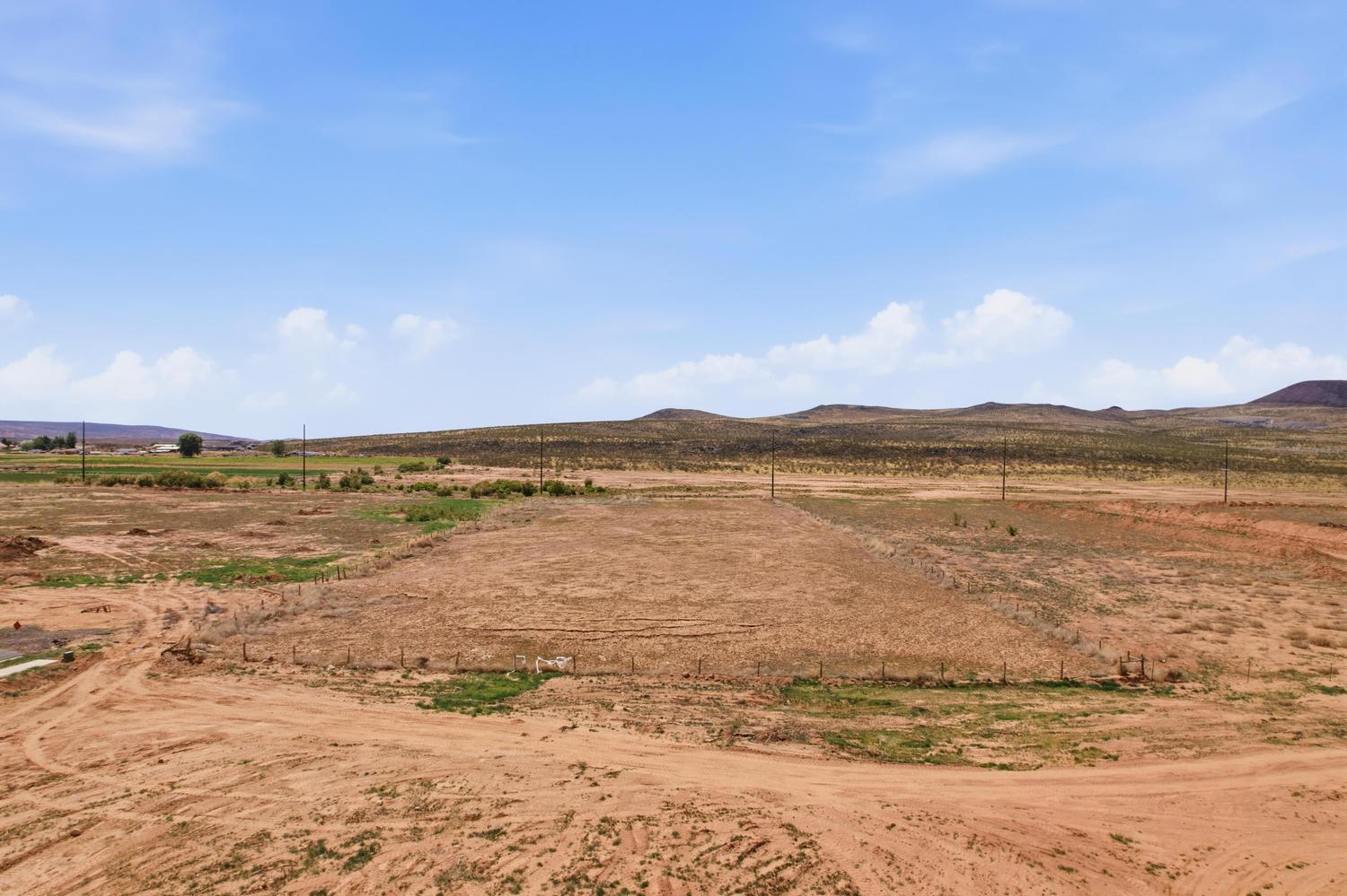 Expansive undeveloped land featuring a dirt terrain and distant rolling hills