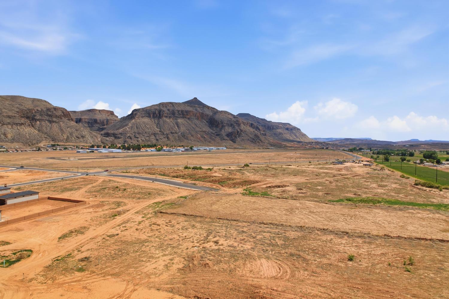 Expansive land parcel featuring existing roadways, a flat topography, and distant mountain backdrops
