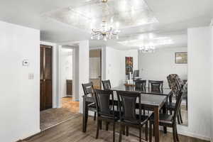Dining area featuring wood-finish flooring, a chandelier with crystal accents, and a mirrored wall panel
