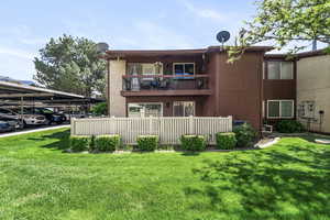Two-story multi-unit dwelling featuring a second-floor balcony, ground-level patio, and a privacy fence