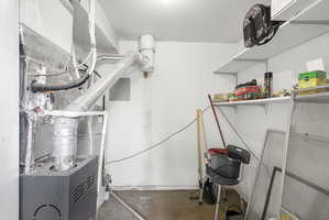 Utility area featuring a furnace system with associated ductwork and shelving
