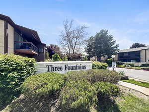 Community entry sign with raised lettering, surrounded by established shrubs and mature trees