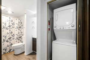 In-unit stackable washer and dryer, wood-finish flooring, and a vanity with a dark wood-finish cabinet and solid surface countertop