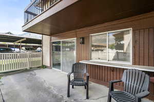 Private concrete patio featuring a lower privacy fence and an upper balcony