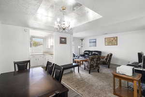 Open-concept living space with a dining area featuring a chandelier and recessed ceiling detail