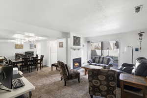 Living area featuring a fireplace with a white mantel, light-toned carpet, and glass sliding doors