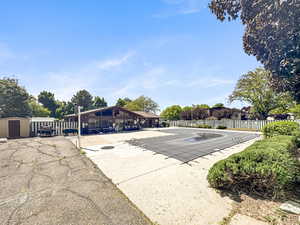 Outdoor swimming pool area featuring a covered pool, surrounding concrete patio, and a recreational building with large windows