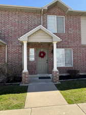 Brick exterior featuring an entryway portico with two columns and a paneled front door