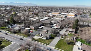 Aerial perspective showcasing a residential and commercial area with multiple properties, a prominent roadway, and distant mountains
