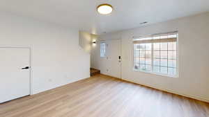 Bright living area featuring wood-finish flooring, white walls, and a large window with white muntins