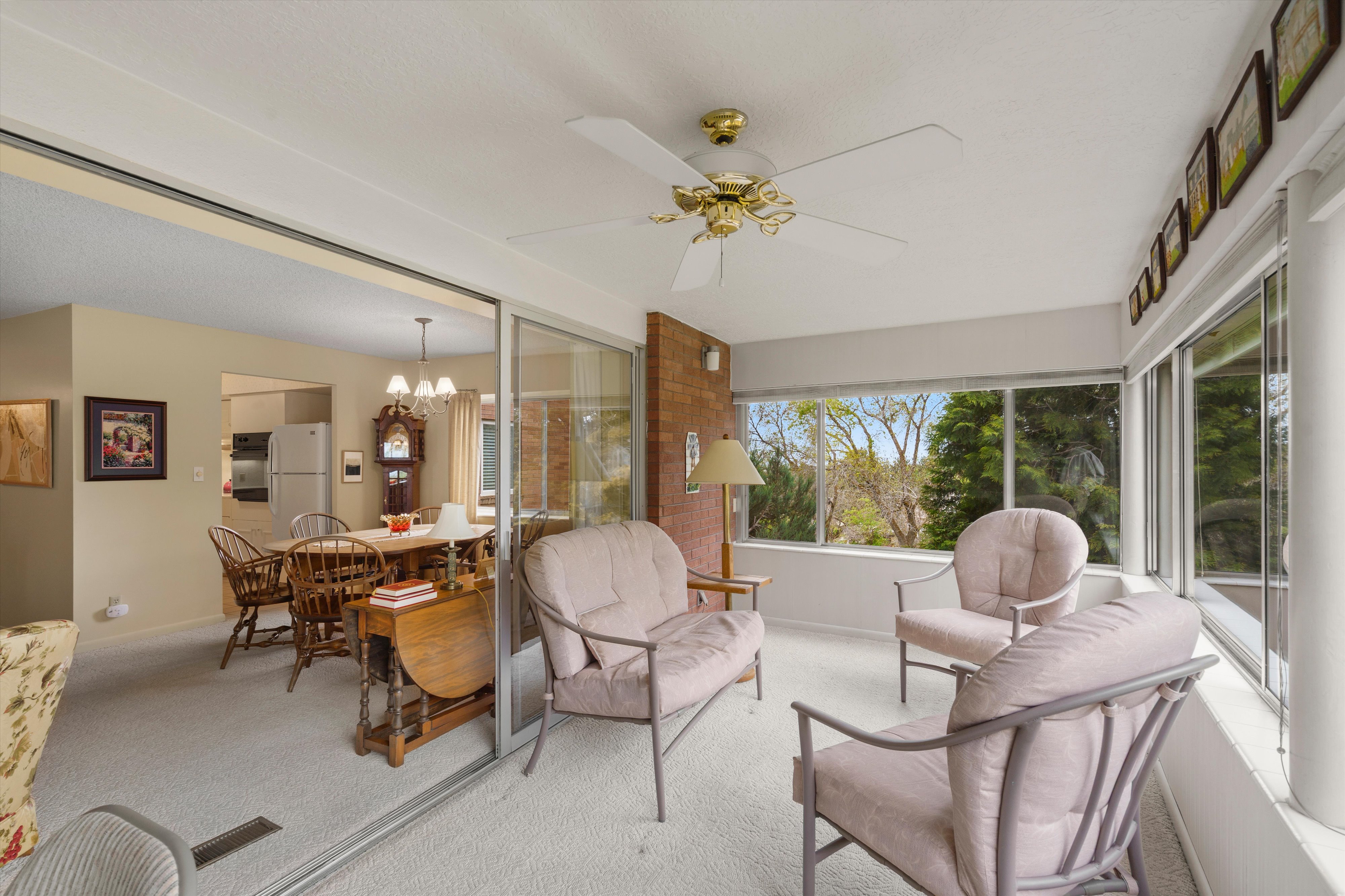 Sunroom featuring wall-to-wall windows, a ceiling fan fixture, and light-colored carpeting