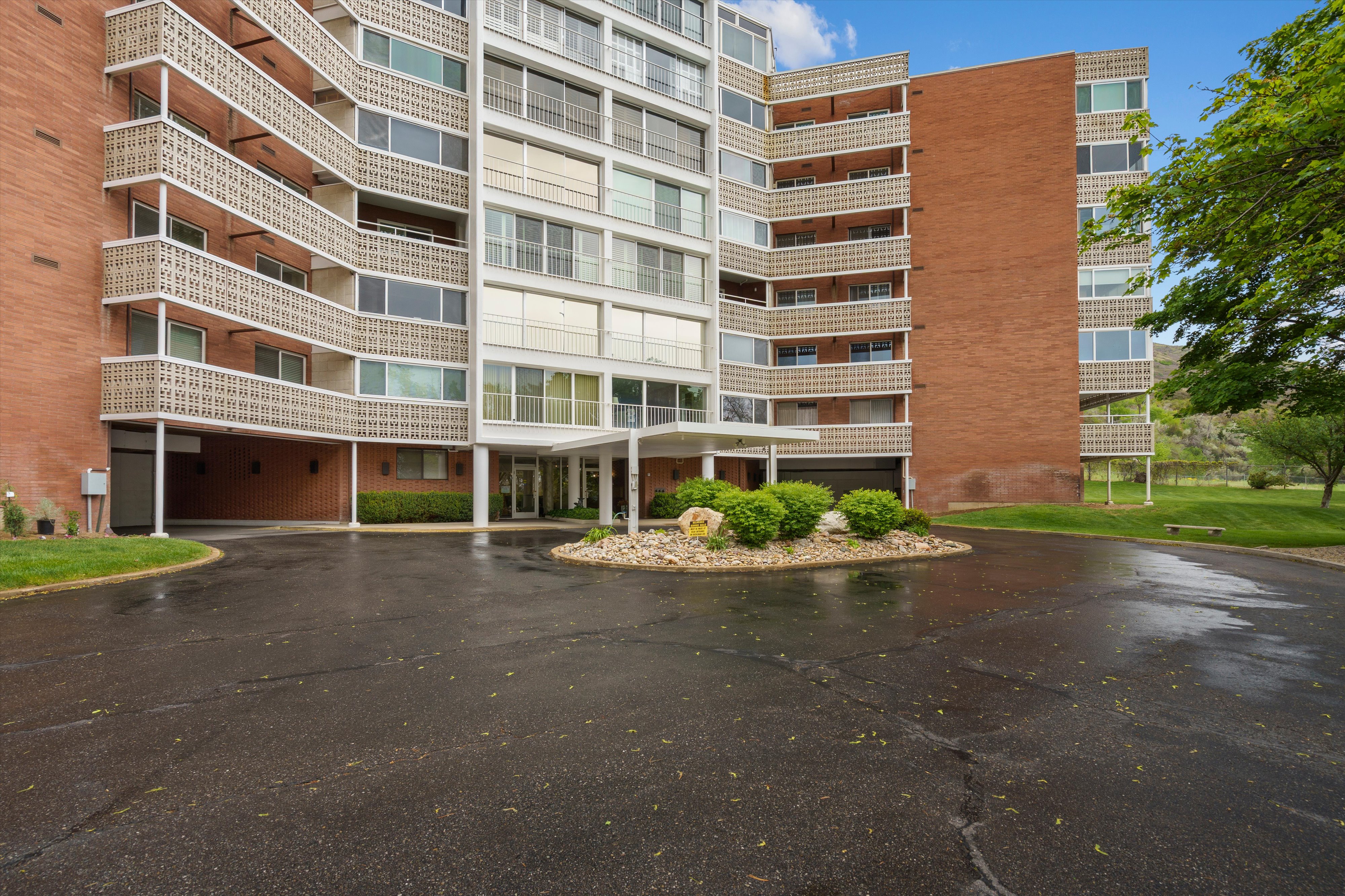 Multi-story apartment building featuring a brick facade, white window trim, and individual balconies with decorative railings