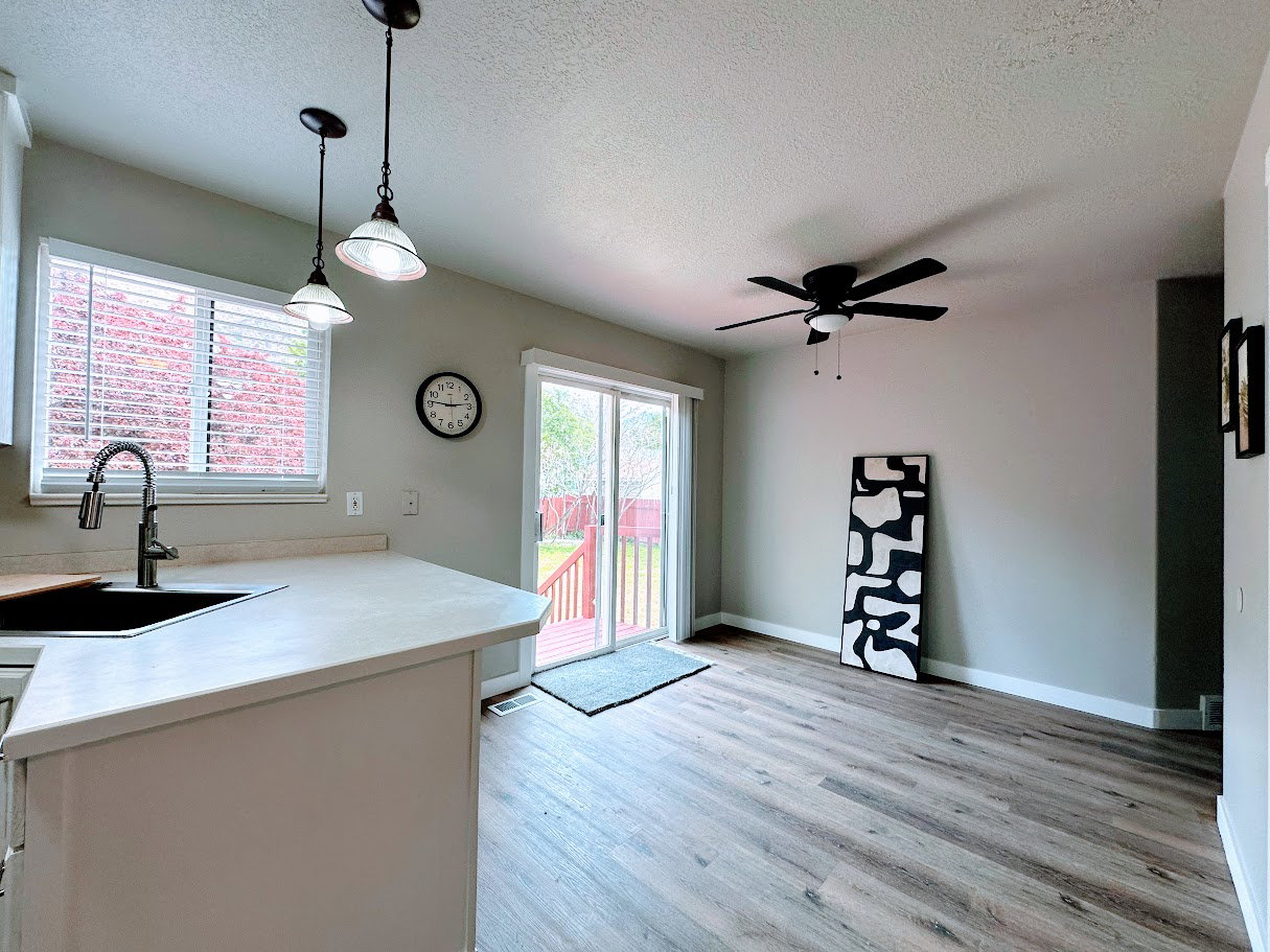 Kitchen and dining area featuring wood-finish flooring, a ceiling fan, pendant lighting, and light-toned countertops