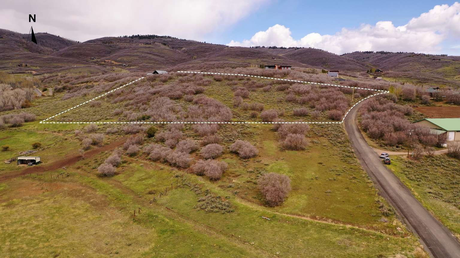 Expansive hillside land parcel with natural vegetation, a clear boundary outline, and direct road frontage