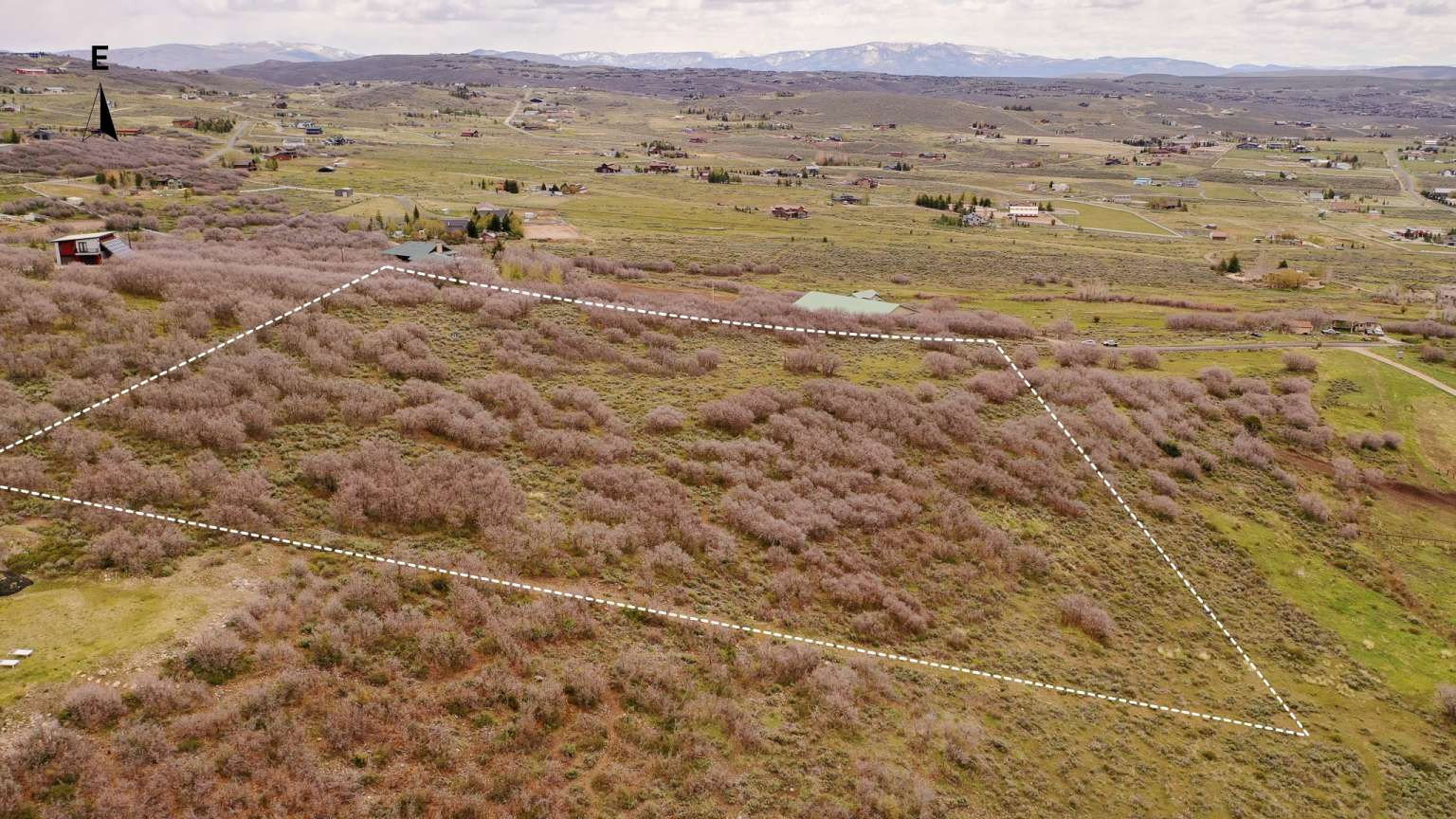 Expansive undeveloped land parcel featuring natural shrubbery and varied terrain