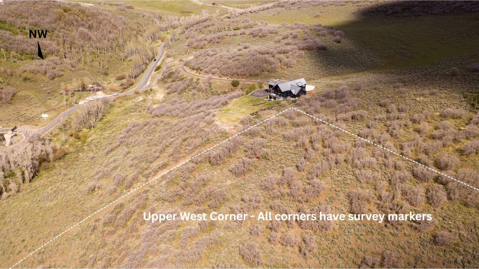 Extensive land parcel featuring natural terrain and a modern home with a dark exterior and light-colored roof