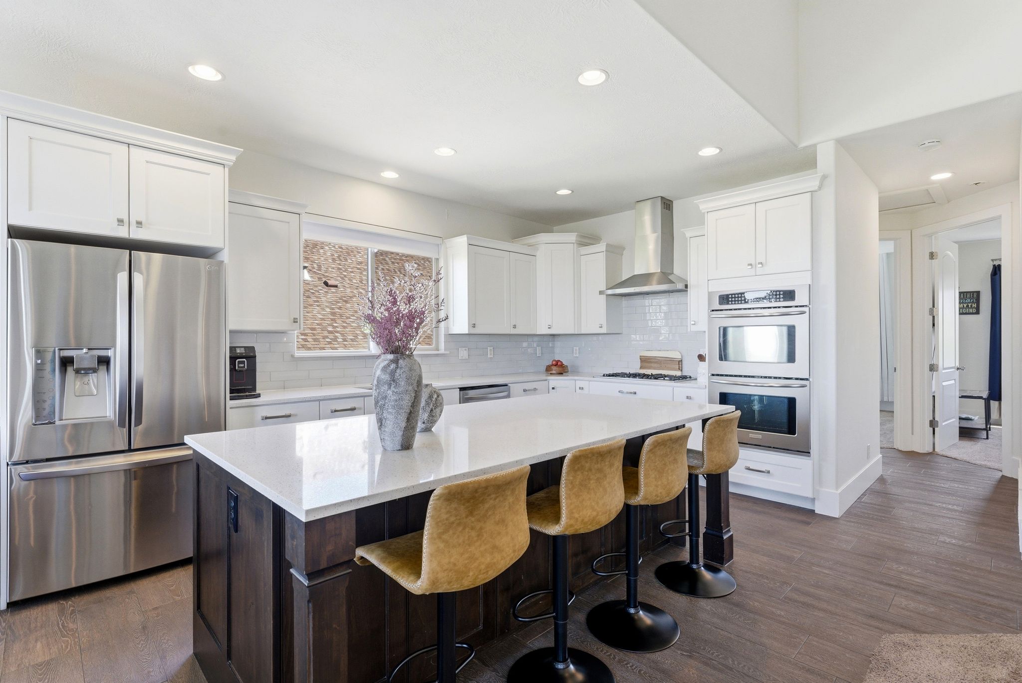 Kitchen featuring stainless steel appliances, dark wood-type flooring, a kitchen island, dual tone cabinetry, and a kitchen bar