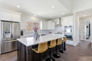 Kitchen featuring stainless steel appliances, dark wood-type flooring, a kitchen island, dual tone cabinetry, and a kitchen bar